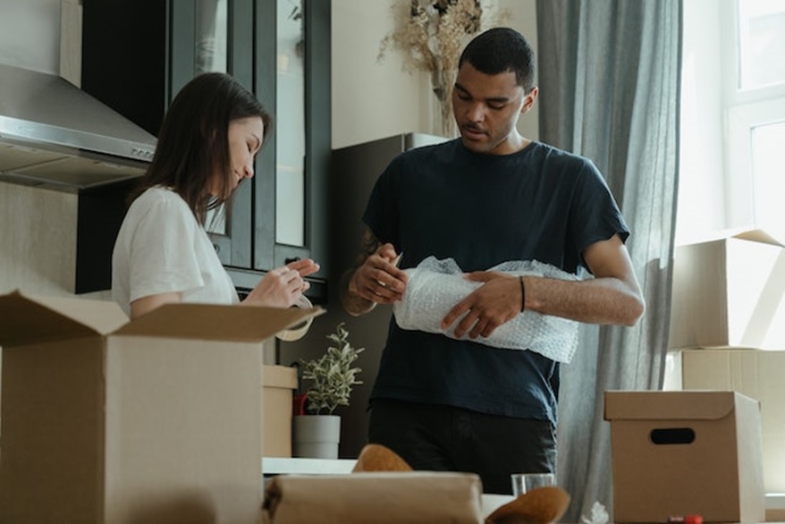 Man and woman packing boxes and using bubble-wrap